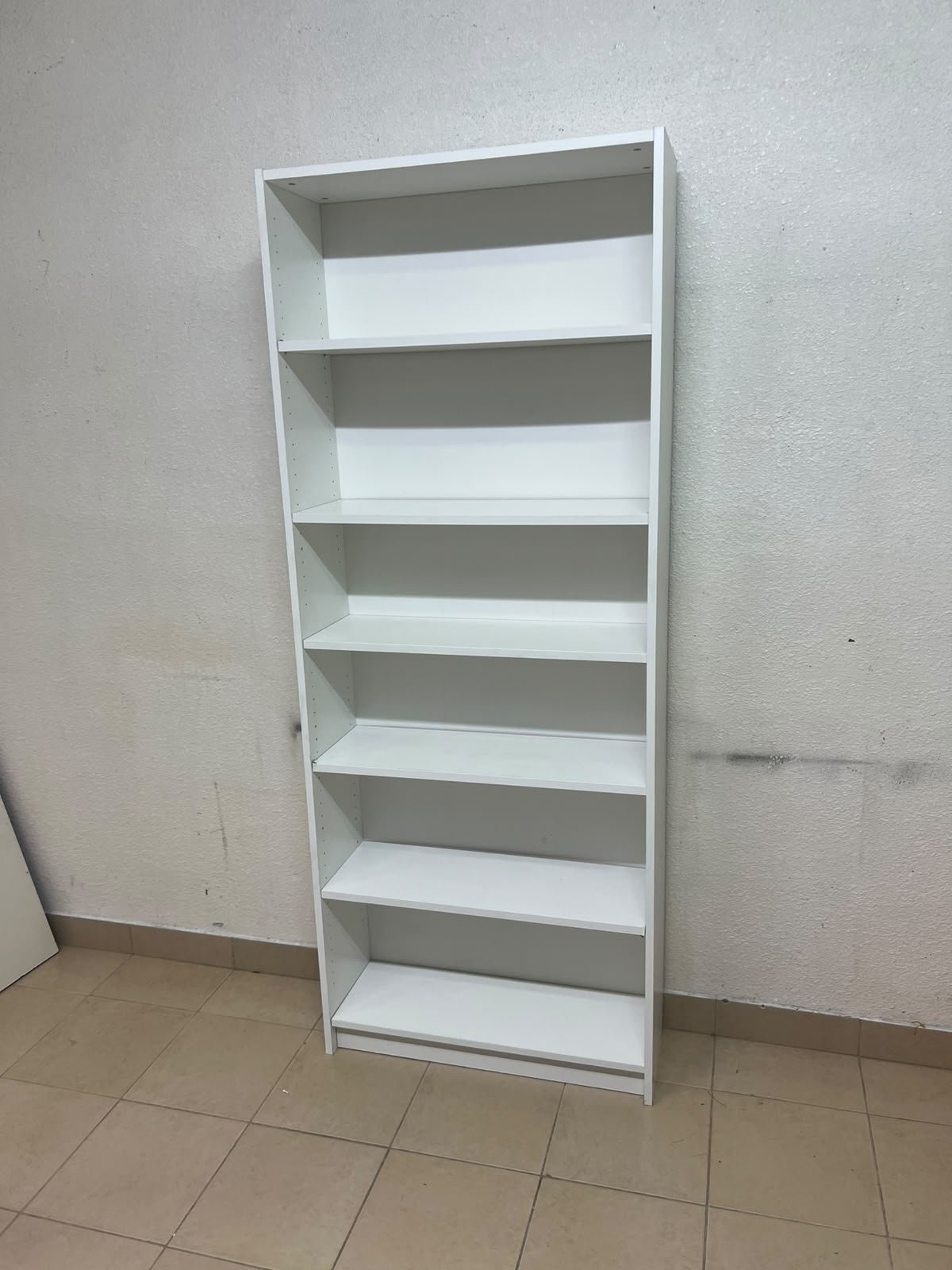 A white bookcase that looks similar to an IKEA BILLY bookcase or other comparable multi-shelf storage units. - Image 3