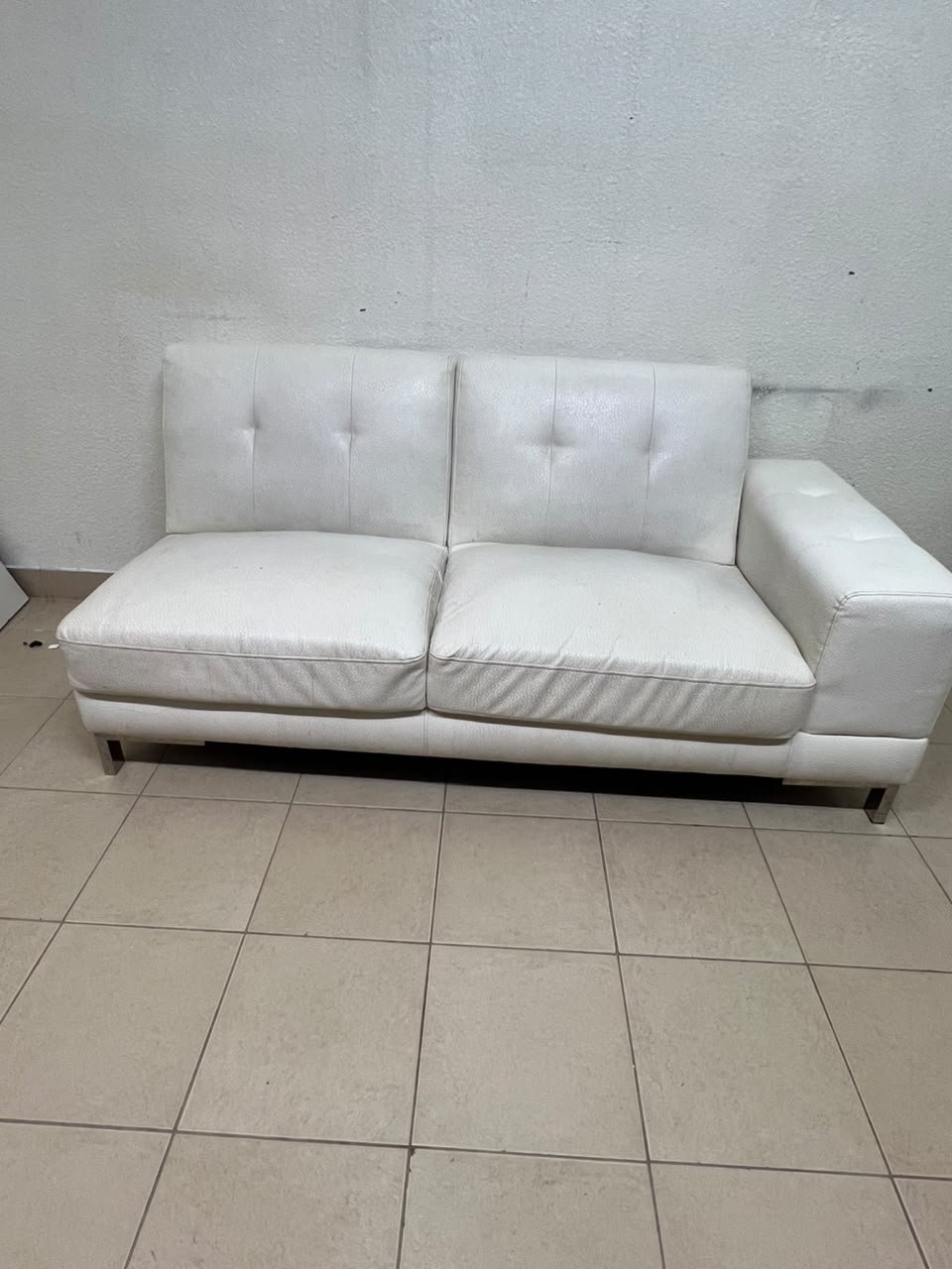 A white faux-leather sofa with a modern design, featuring button-tufted back cushions and slender metal legs. - Image 2