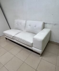 A white faux-leather sofa with a modern design, featuring button-tufted back cushions and slender metal legs. - Image 5