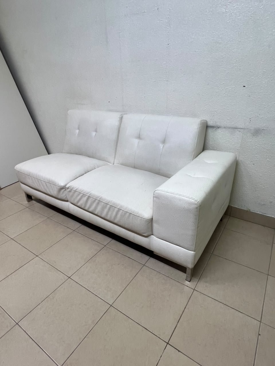 A white faux-leather sofa with a modern design, featuring button-tufted back cushions and slender metal legs. - Image 5