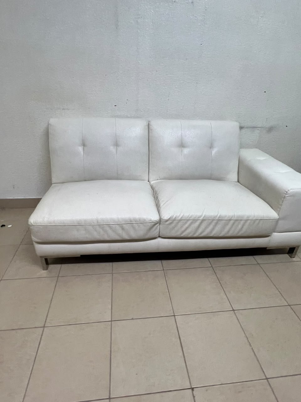 A white faux-leather sofa with a modern design, featuring button-tufted back cushions and slender metal legs. - Image 6