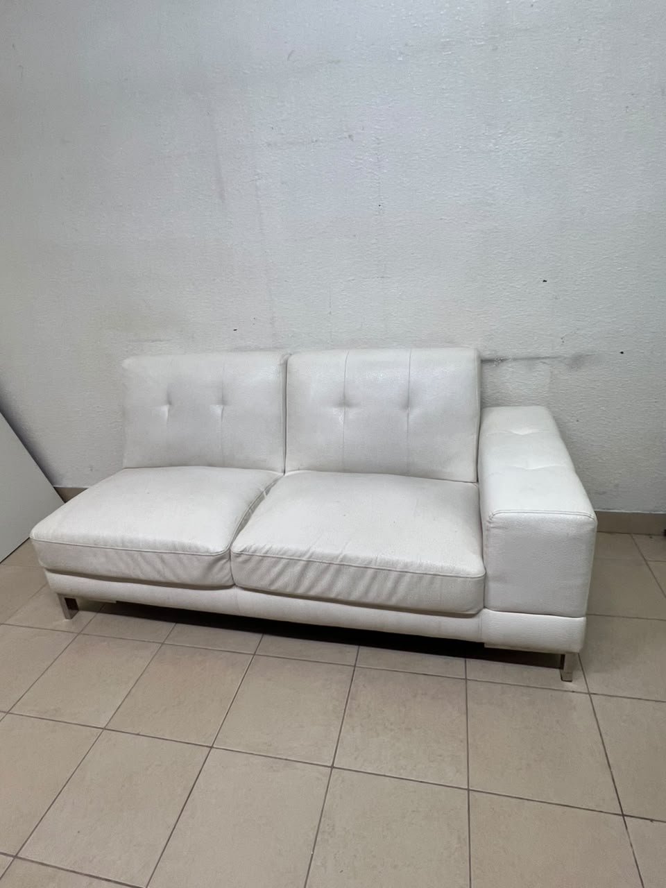 A white faux-leather sofa with a modern design, featuring button-tufted back cushions and slender metal legs. - Image 8