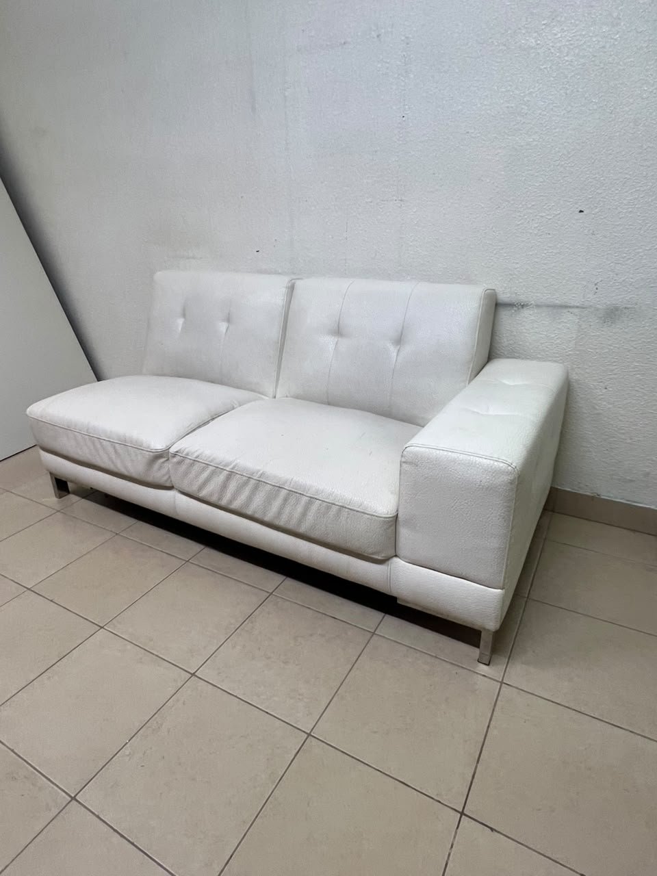 A white faux-leather sofa with a modern design, featuring button-tufted back cushions and slender metal legs. - Image 9