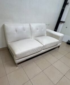 A white faux-leather sofa with a modern design, featuring button-tufted back cushions and slender metal legs. - Image 3