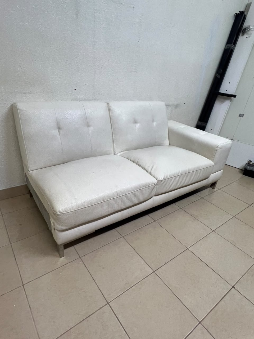 A white faux-leather sofa with a modern design, featuring button-tufted back cushions and slender metal legs. - Image 3