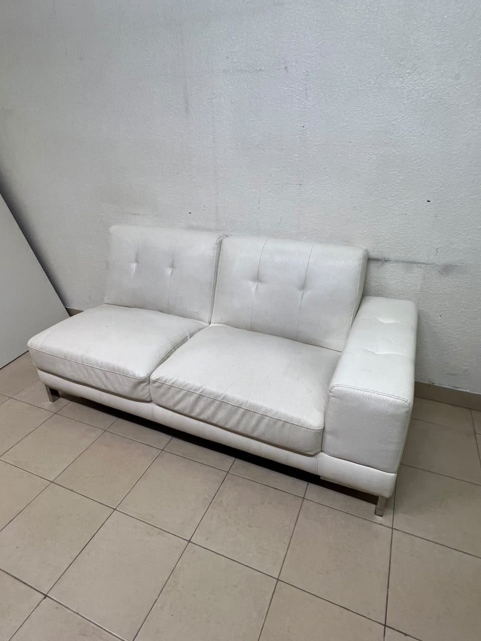 A white faux-leather sofa with a modern design, featuring button-tufted back cushions and slender metal legs. - Image 4